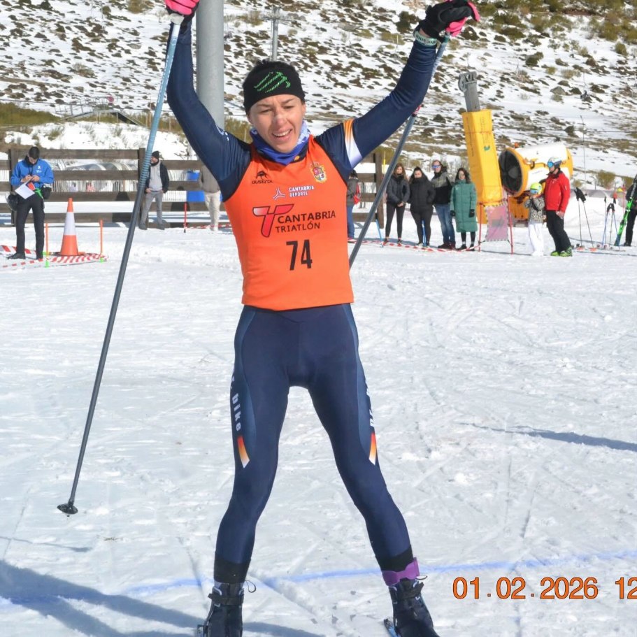 Ana Gay crossing the finish on cross-country skis with her arms raised
